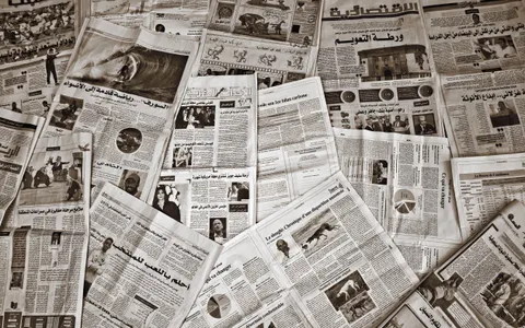A variety of Arabic and French newspapers spread out, showcasing diverse articles and images.